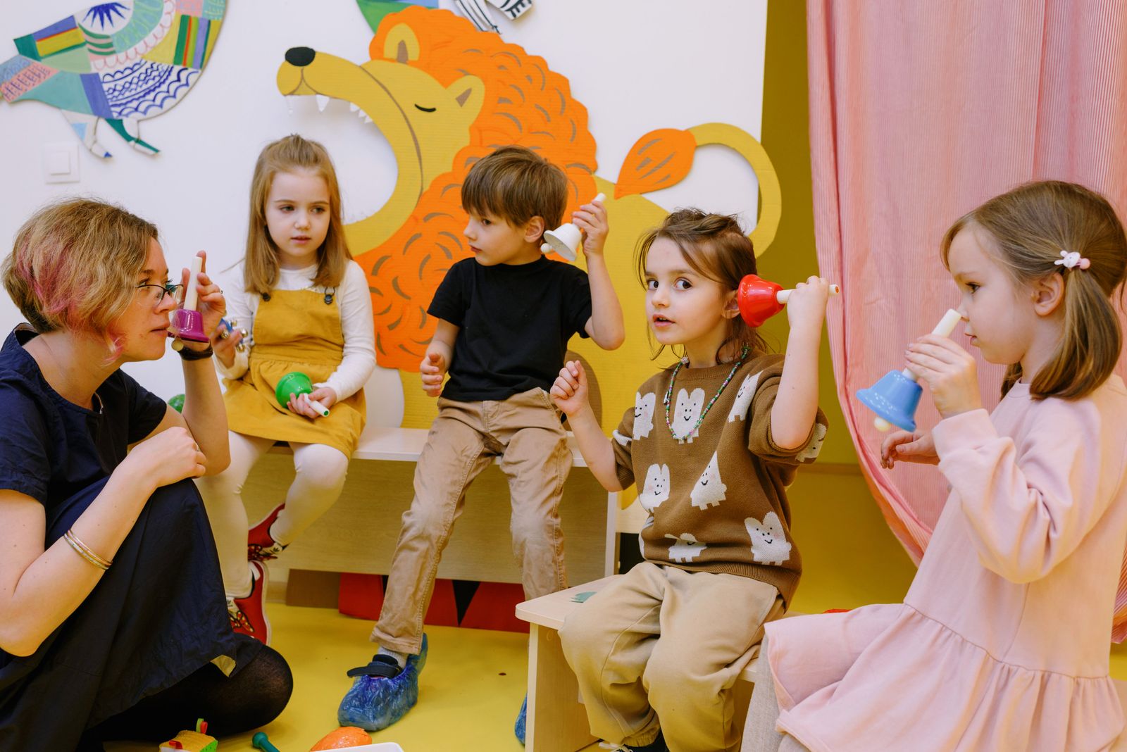 Preschool children playing colourful musical bells with a teacher